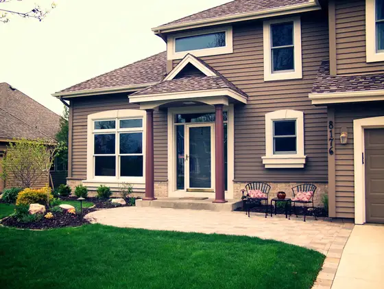 Two-story home with a paver front entry patio, foundation plantings, and a freshly cut front lawn