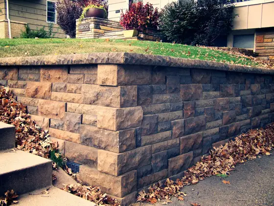 Tumbled block retaining wall with capstone coping running along a driveway