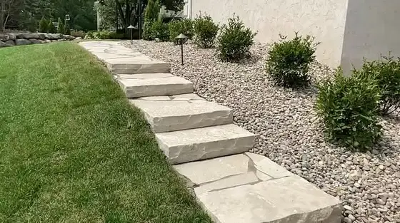Natural flagstone steps set into a river-rock bed beside a manicured lawn