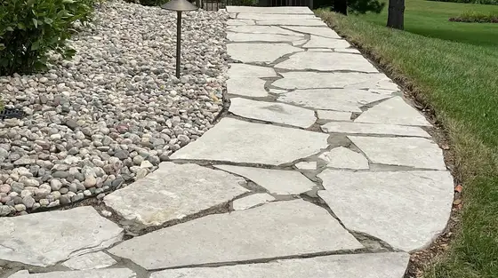 Natural flagstone walkway edged with river-rock landscaping beside a manicured lawn